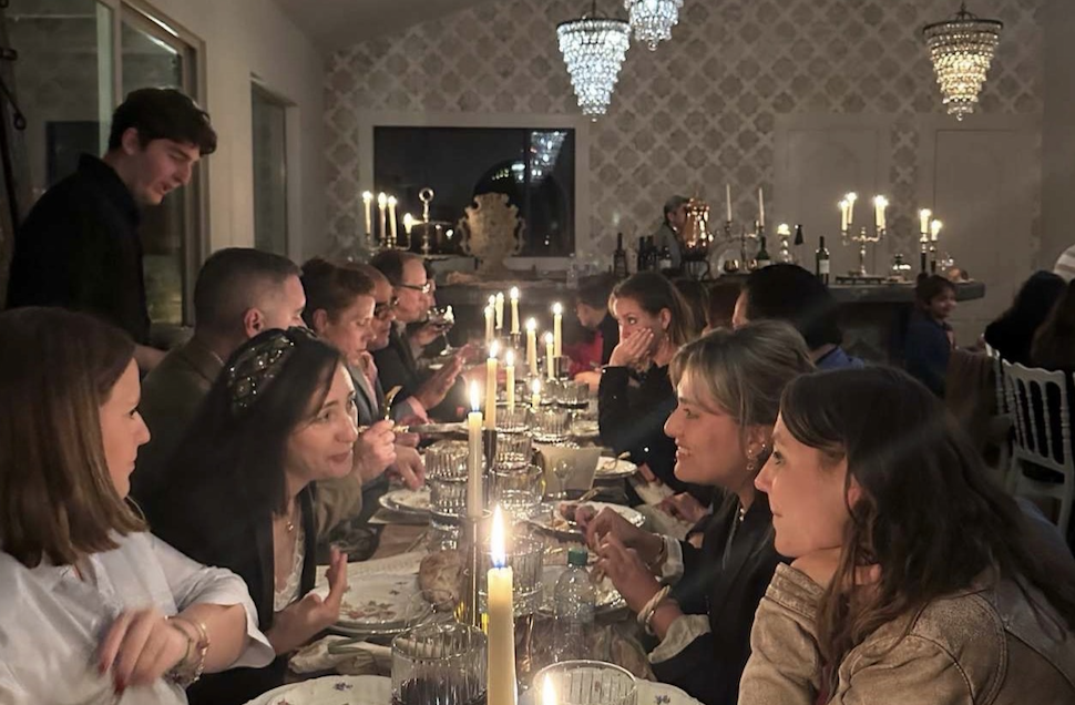 Guests gathered at a long candlelit dinner under chandeliers
