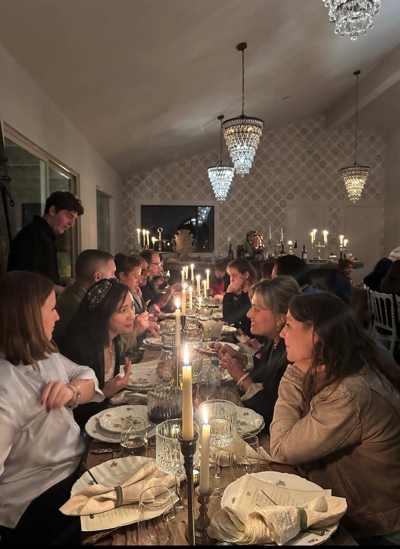 Candlelit dinner with guests under chandeliers